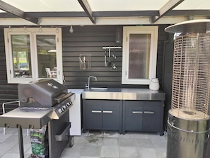 A compact outdoor kitchen with a grill, sink, and storage cabinets.