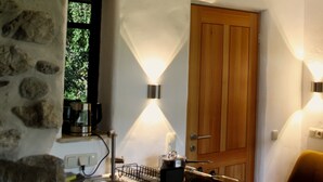 A kitchen with a stone wall, wooden door, and a window. - Vacation apartment with terrace and mountain view (Frasdorf)