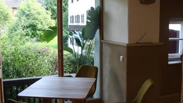 Ein Essbereich mit Tisch und Stühlen, eine Küchenzeile mit Herd sowie Blick auf Grünflächen außerhalb.