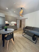 A modern kitchen with grey cabinets, a round dining table with two chairs, a grey sofa, and a small coffee table.