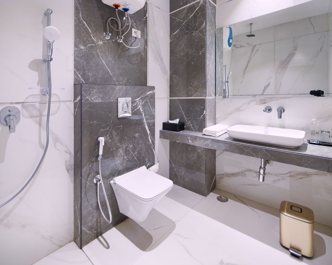 Une salle de bain moderne avec une douche en marbre, des toilettes blanches, un lavabo avec un miroir et une douchette à main.