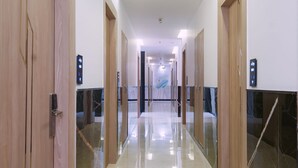 Un pasillo con puertas de madera y barandas de cristal que conduce a una habitación con una cama y un ventanal grande.