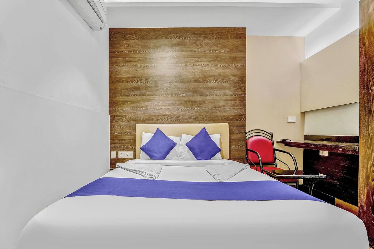 A neatly made bed with a blue and white bedspread, two blue pillows, and a wooden headboard.