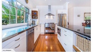 A modern kitchen with white cabinets, stainless steel appliances, and a wooden floor.