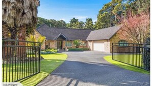 A two-story house with a driveway leading to a garage, surrounded by a well-maintained lawn and trees.