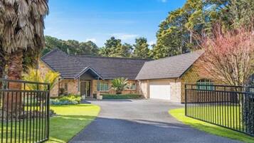A two-story house with a driveway leading to a garage, surrounded by a well-maintained lawn and trees.