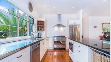 A modern kitchen with white cabinets, stainless steel appliances, and a wooden floor.