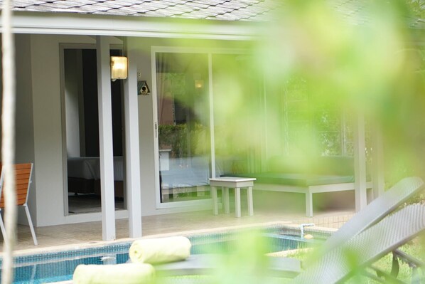 A pool area with a lounge chair, a small table, and a bench.