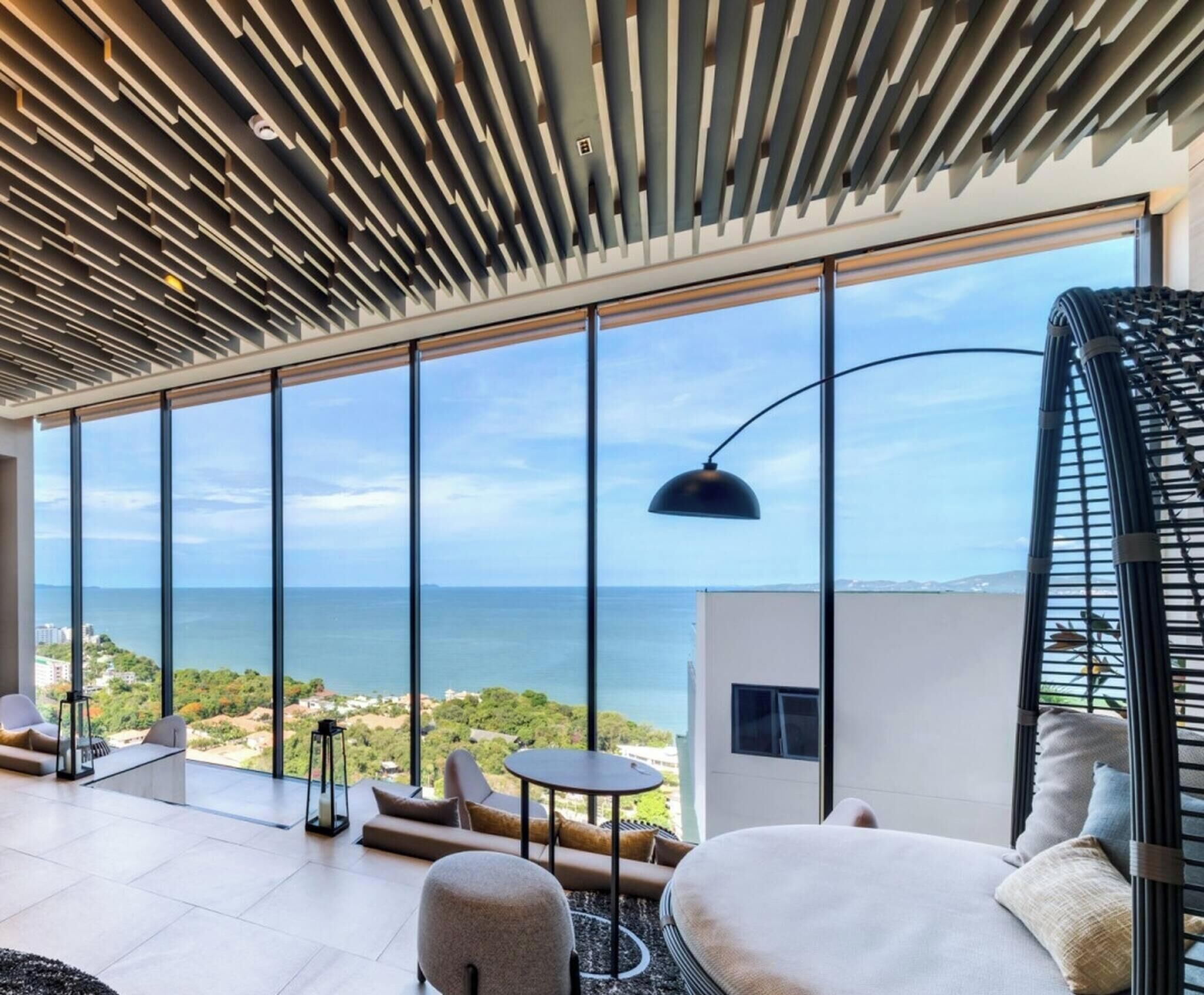 Ein modernes Interieur mit großen Fenstern, einem runden Tisch und Blick aufs Meer.