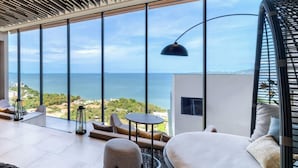A modern room with a large window overlooking the sea, a round table, and a sofa. - Sea View At The Beach Front - Breathtaking View (Muang Pattaya)