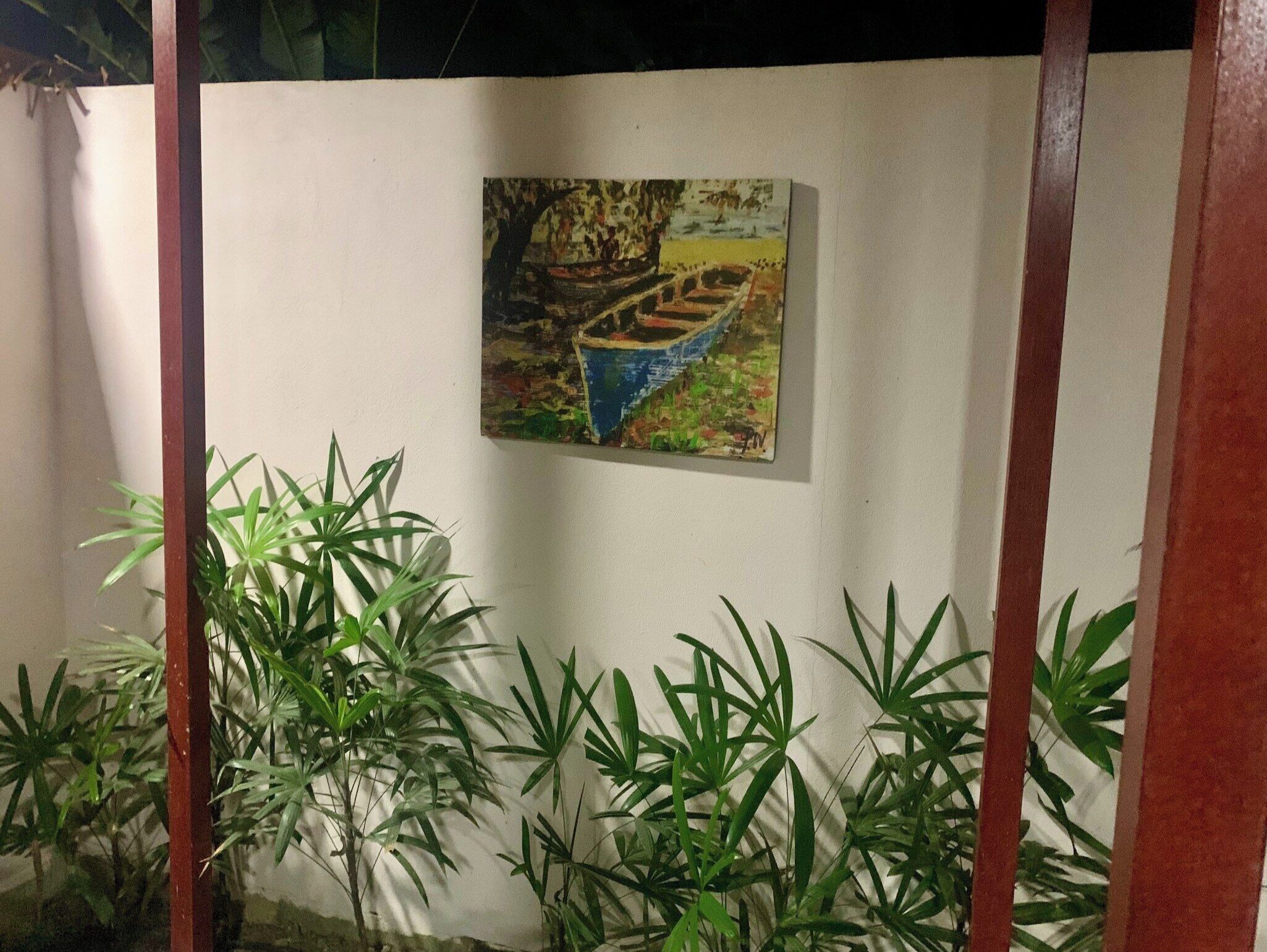 Pintura d'una embarcació a la paret, envoltada de plantes verdes.