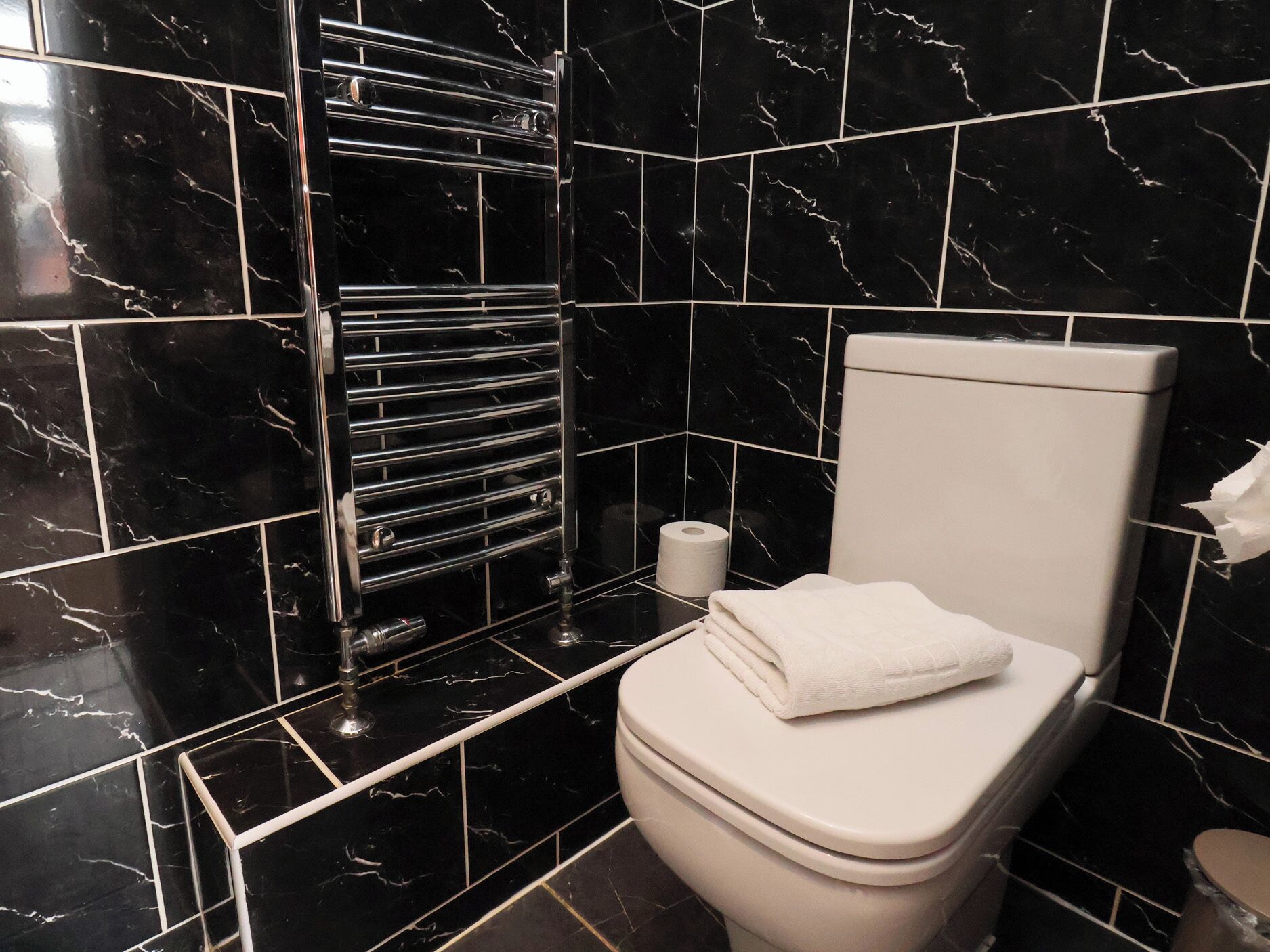 A bathroom with a toilet, a towel, and a toilet paper roll.