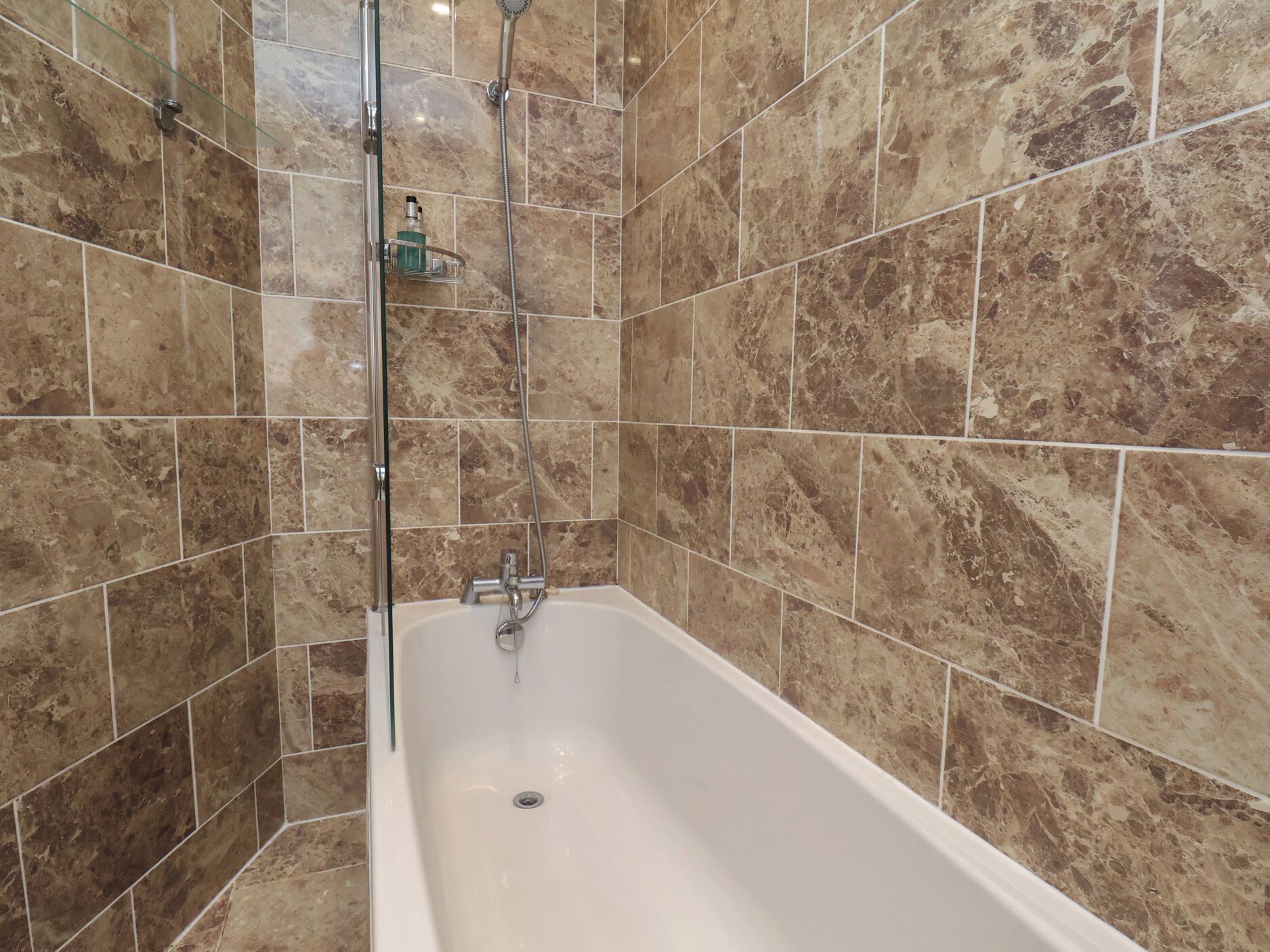 A bathroom with a freestanding bathtub, a glass shower enclosure, and a marble-tiled wall.