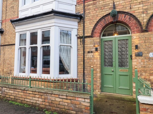 A traditional brick building with a green door and a bay window.