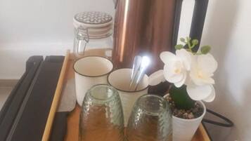 A tray with a coffee pot, two cups, a jar, and a potted plant.