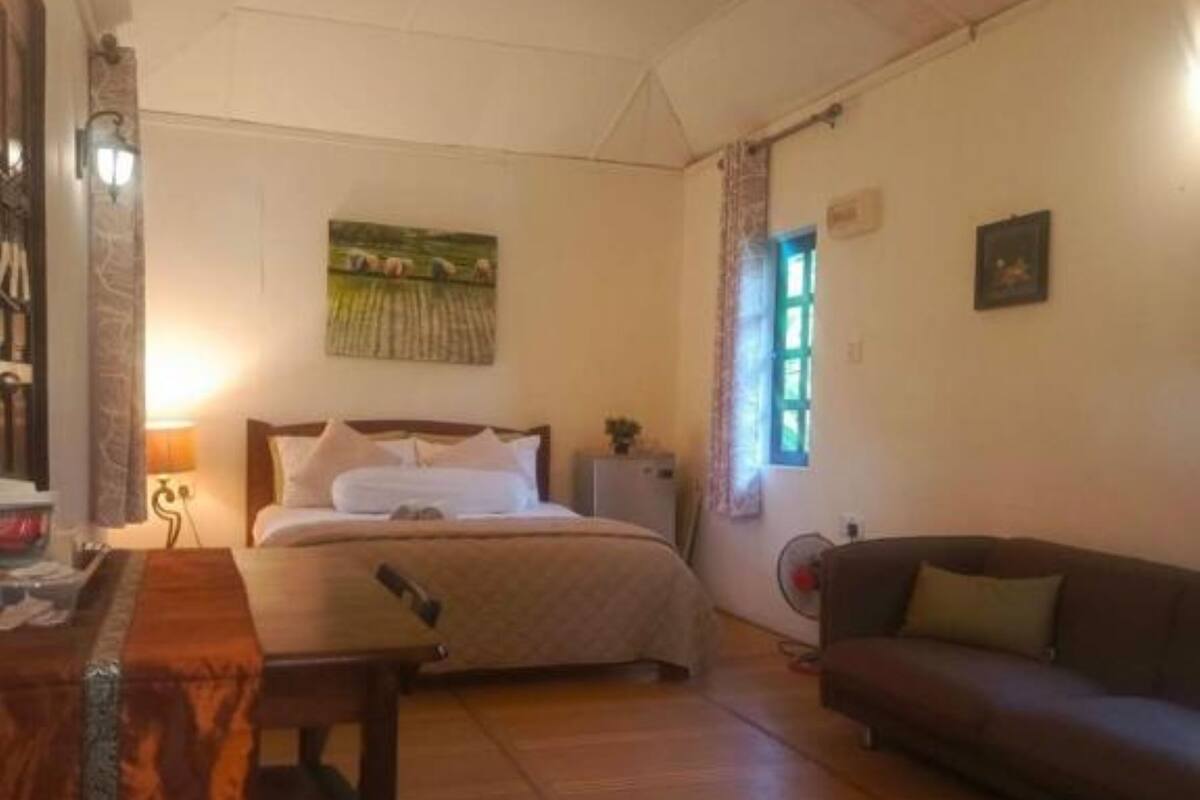Une chambre à coucher avec un lit, un bureau en bois, un canapé et un tableau accroché au mur.