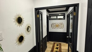 A hallway with black trim, white walls, and a patterned rug leading to a door. - Casa Dela Tierra by Araw Residences (Mambajao)