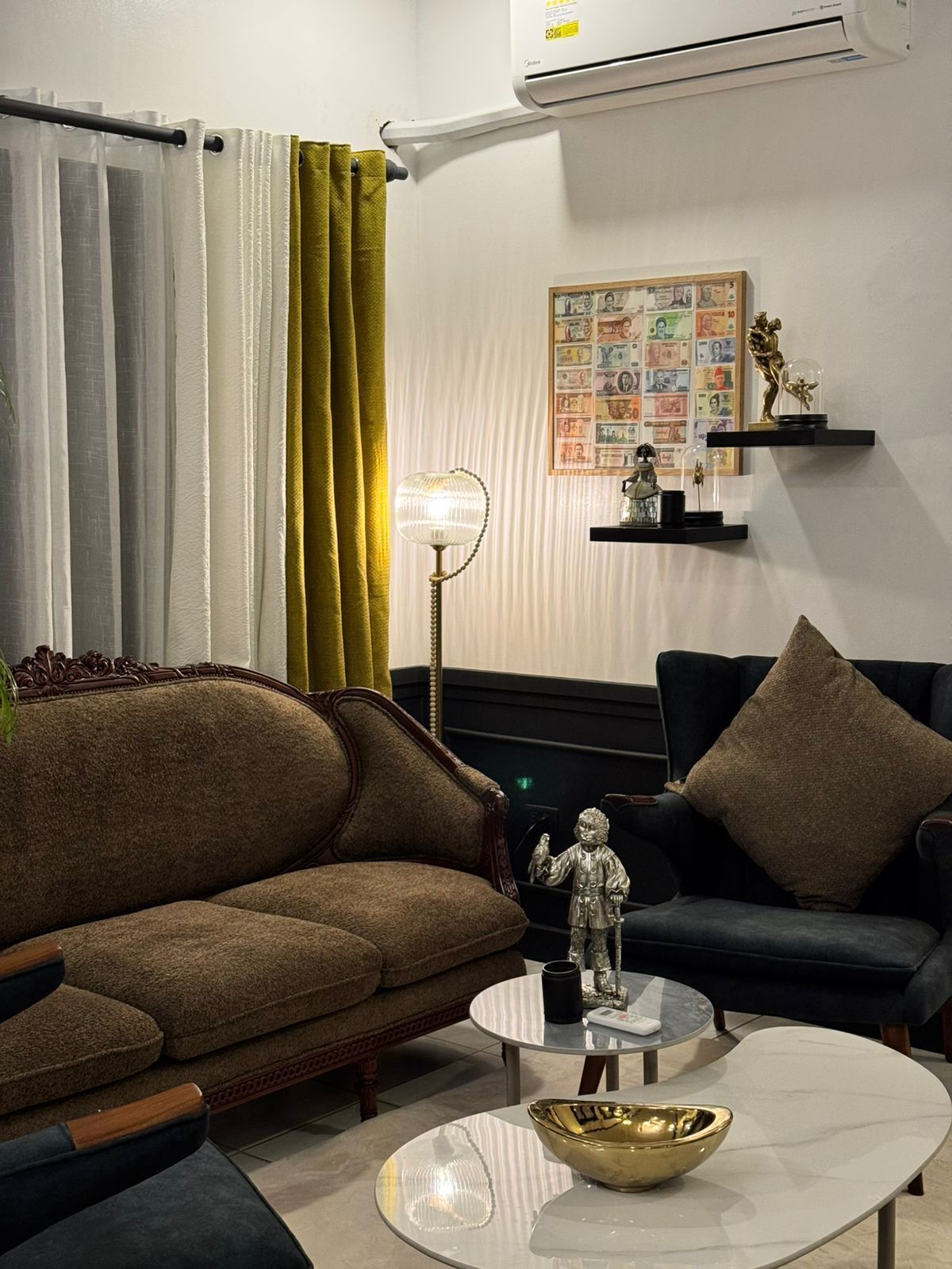A living room with a brown sofa, a black sofa, a round coffee table, and a small table with decorative items.