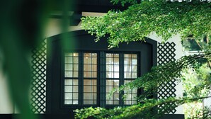 A building with a dark facade, a window with multiple panes, and a lattice design on the side. - Casa Dela Tierra by Araw Residences (Mambajao)