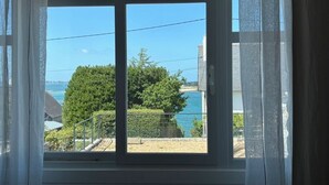 A window with a view of a tree and a body of water. - 3* Apartment for 2–4 people, 25 m² terrace—50 m from the beach and the GR34 trail. Dogs Welcome (Carantec)
