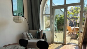 A cozy living room with a sofa, a dining table, and a large window. - 3* Apartment for 2–4 people, 25 m² terrace—50 m from the beach and the GR34 trail. Dogs Welcome (Carantec)