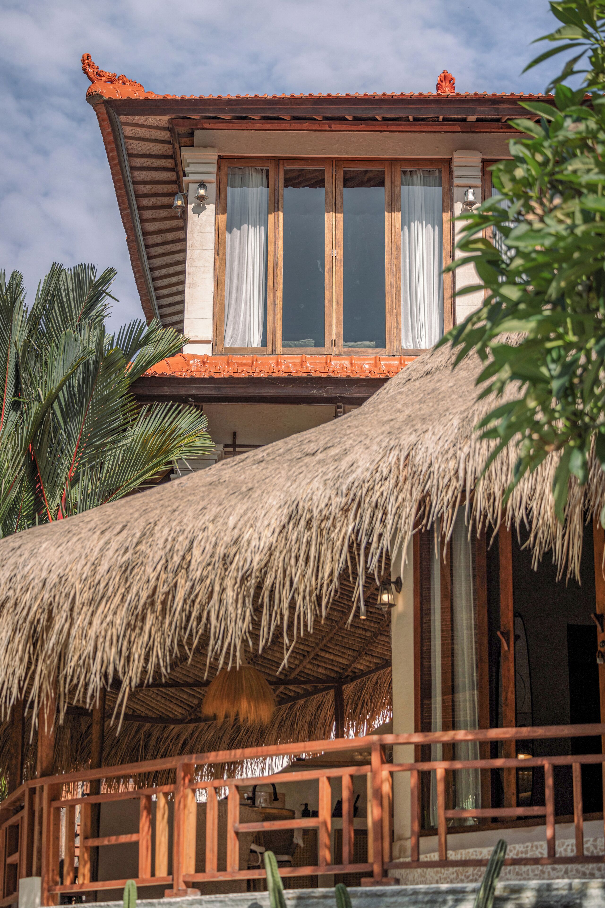 A two-story building with a thatched roof and wooden balcony railings.