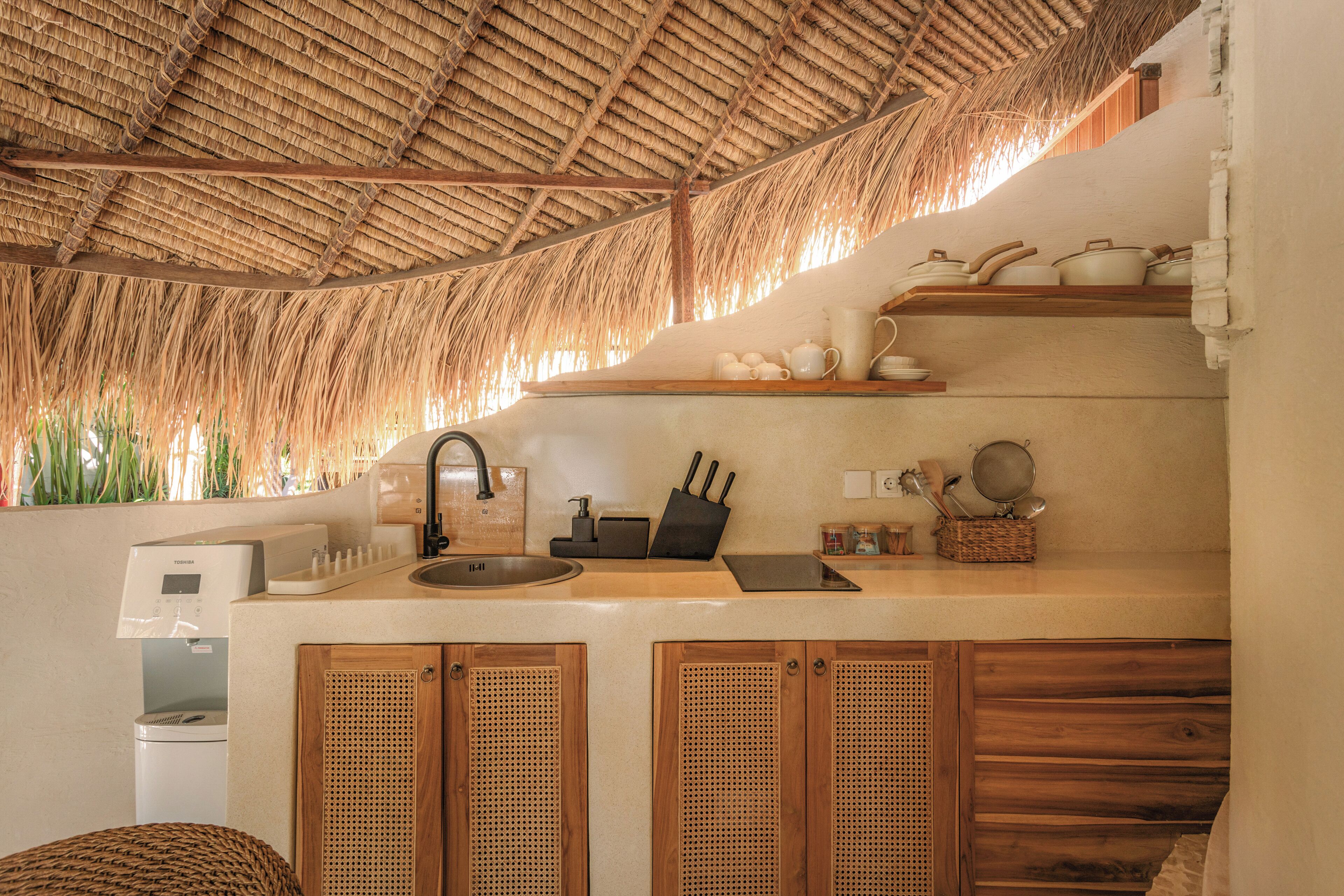 Una cucina con tetto di paglia, mobili in legno e un distributore d'acqua.