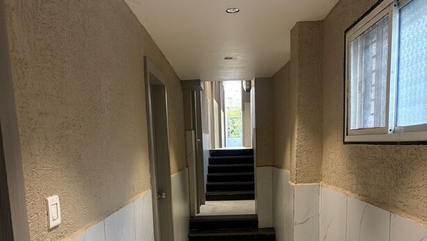 En hall med marmorgolv, en trappa och ett fönster med utsikt.