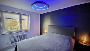 A bedroom with a bed, a window, a radiator, and two bedside lamps.