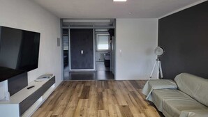 A modern living room with a flat-screen TV, a sofa, and a tripod.