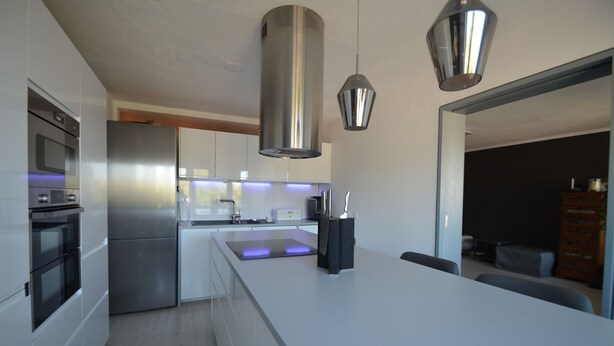 A modern kitchen with stainless steel appliances, a central island, and pendant lighting.