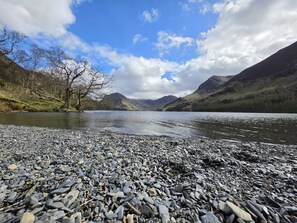 A rocky shoreline with a lake, mountains, and a clear sky. -  Ample Town house nestled in the Lake District, Workington. Your home-from-home (Workington)