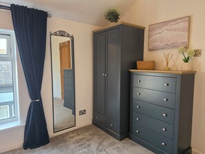 Une pièce dotée d’une grande armoire, d’un miroir, d’une fenêtre avec des rideaux et d’un tableau accroché au mur.