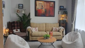 Una sala de estar con un sofá color crema, dos sillones, una mesita de centro y un cuadro en la pared.
