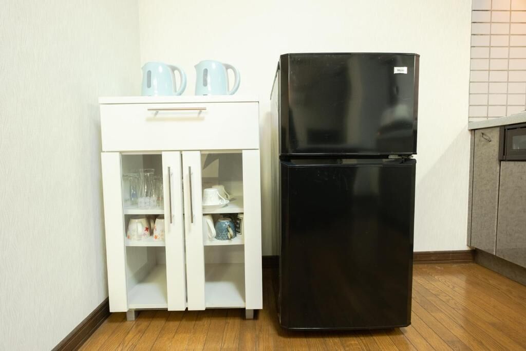 A compact kitchen with a white cabinet and a black refrigerator.