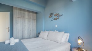 A bedroom with a bed, a nightstand, a wall-mounted lamp, a wardrobe, and a decorative fish wall art piece. - Apartment 'Emelia' with Sea View, Wi-Fi and Air Conditioning (Lixouri)