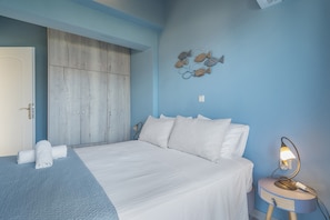 Ein Schlafzimmer mit einem Bett, einem Nachttisch, einer Wandlampe, einem Kleiderschrank und einem Wandbild mit Fischen.