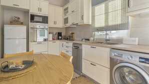 A compact kitchen with white cabinets, a microwave, oven, coffee maker, and a washing machine. - Apartment 'Emelia' with Sea View, Wi-Fi and Air Conditioning (Lixouri)