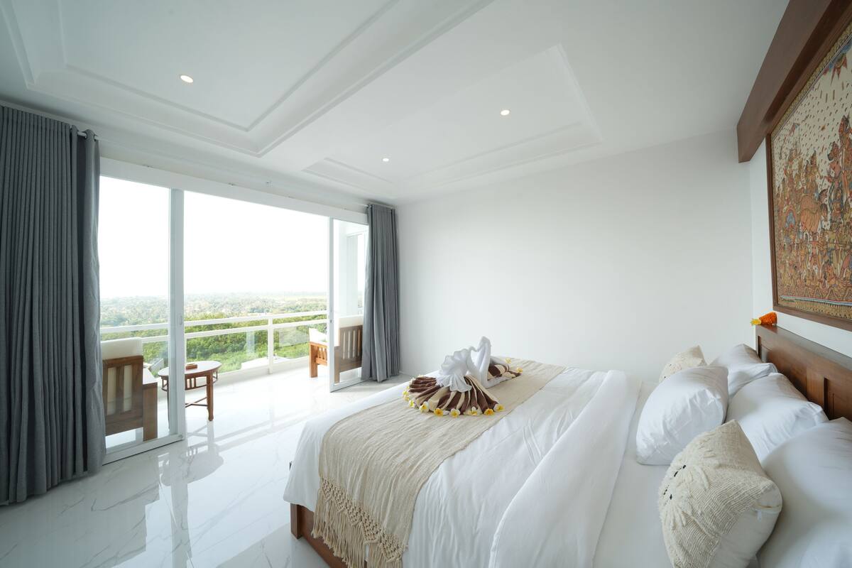 Ein geräumiges Schlafzimmer mit einem großen Bett, einem Balkon mit Blick und einem Essbereich.