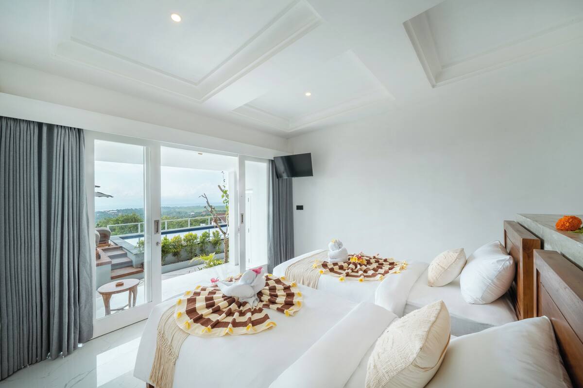 Ein modernes Hotelzimmer mit einer großen Schiebeglasdoor, die auf einen Balkon mit schöner Aussicht führt.