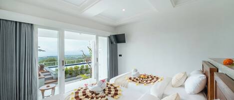 Habitación de hotel moderna con un amplio ventanal corredera que da a un balcón y vistas panorámicas.