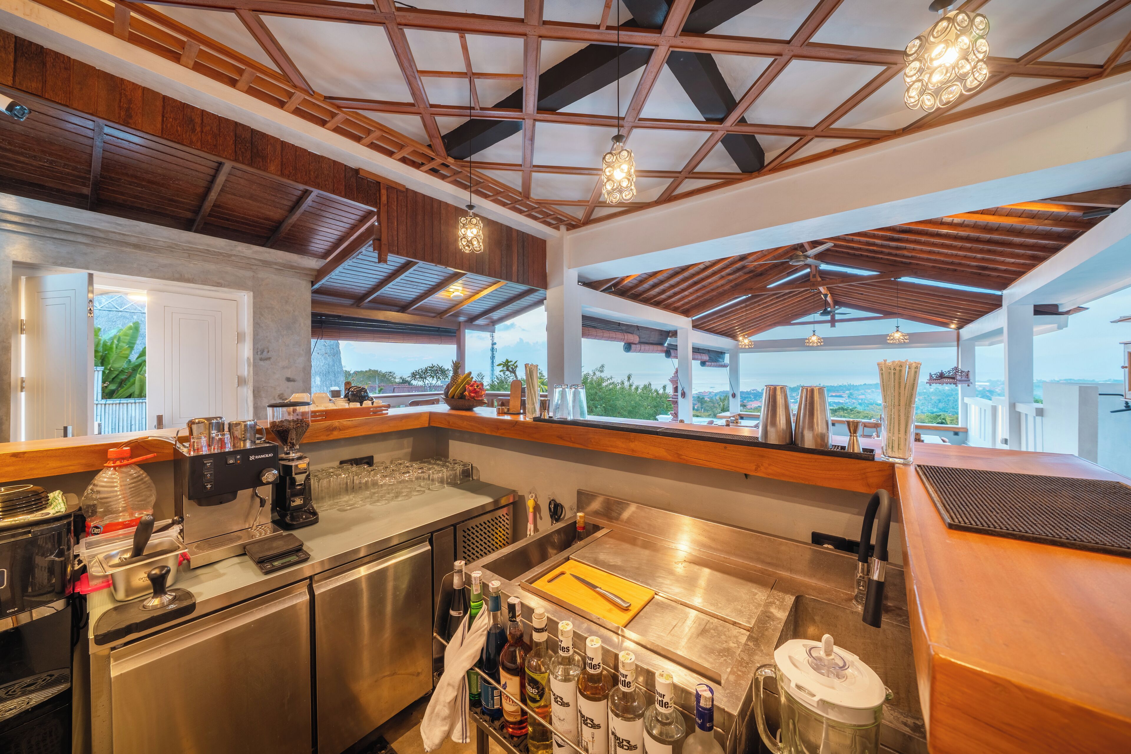 A modern kitchen with stainless steel appliances, a wooden ceiling, and a view of the outdoors.