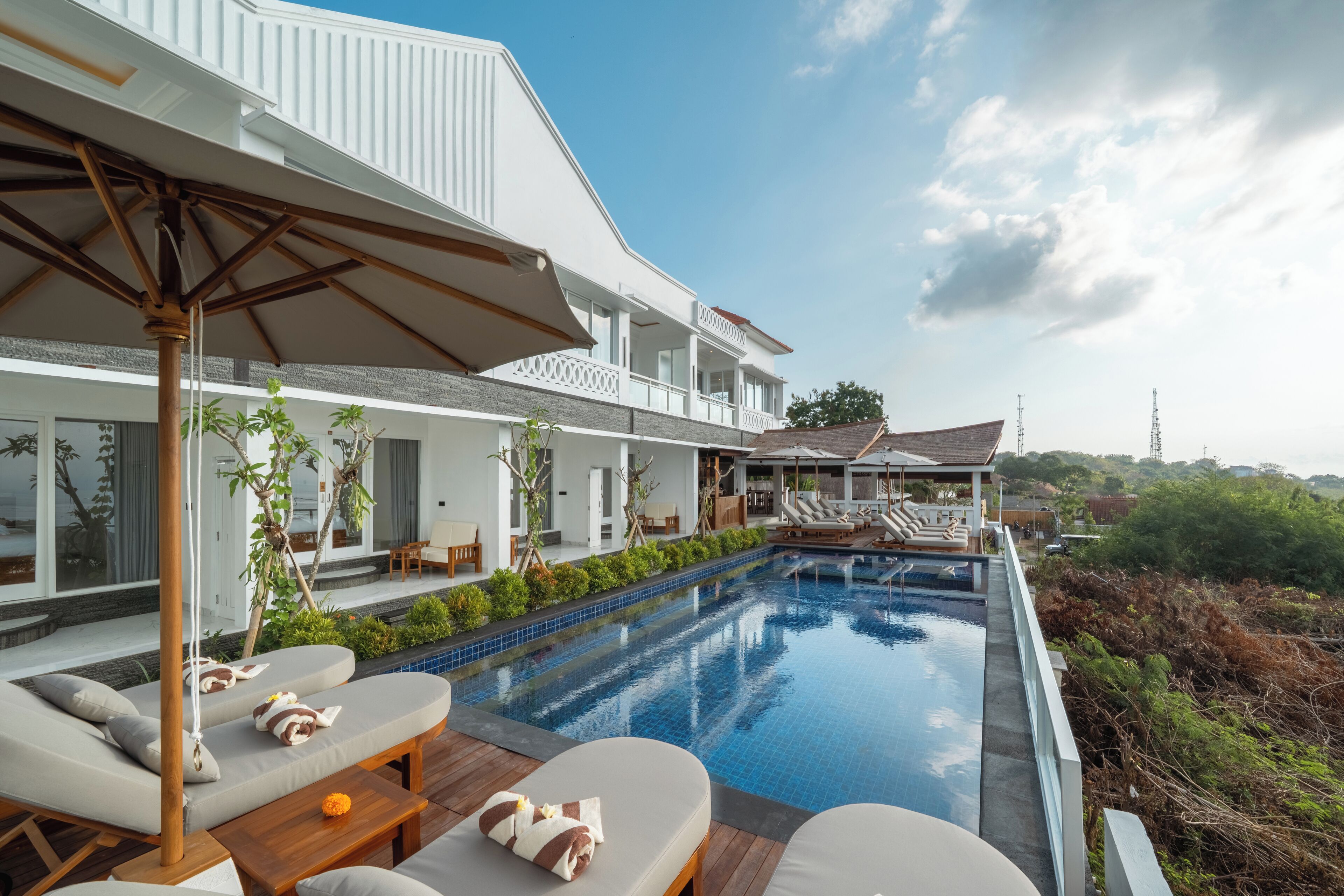 Un moderno resort con piscina, sillas de descanso y un área de patio techada.