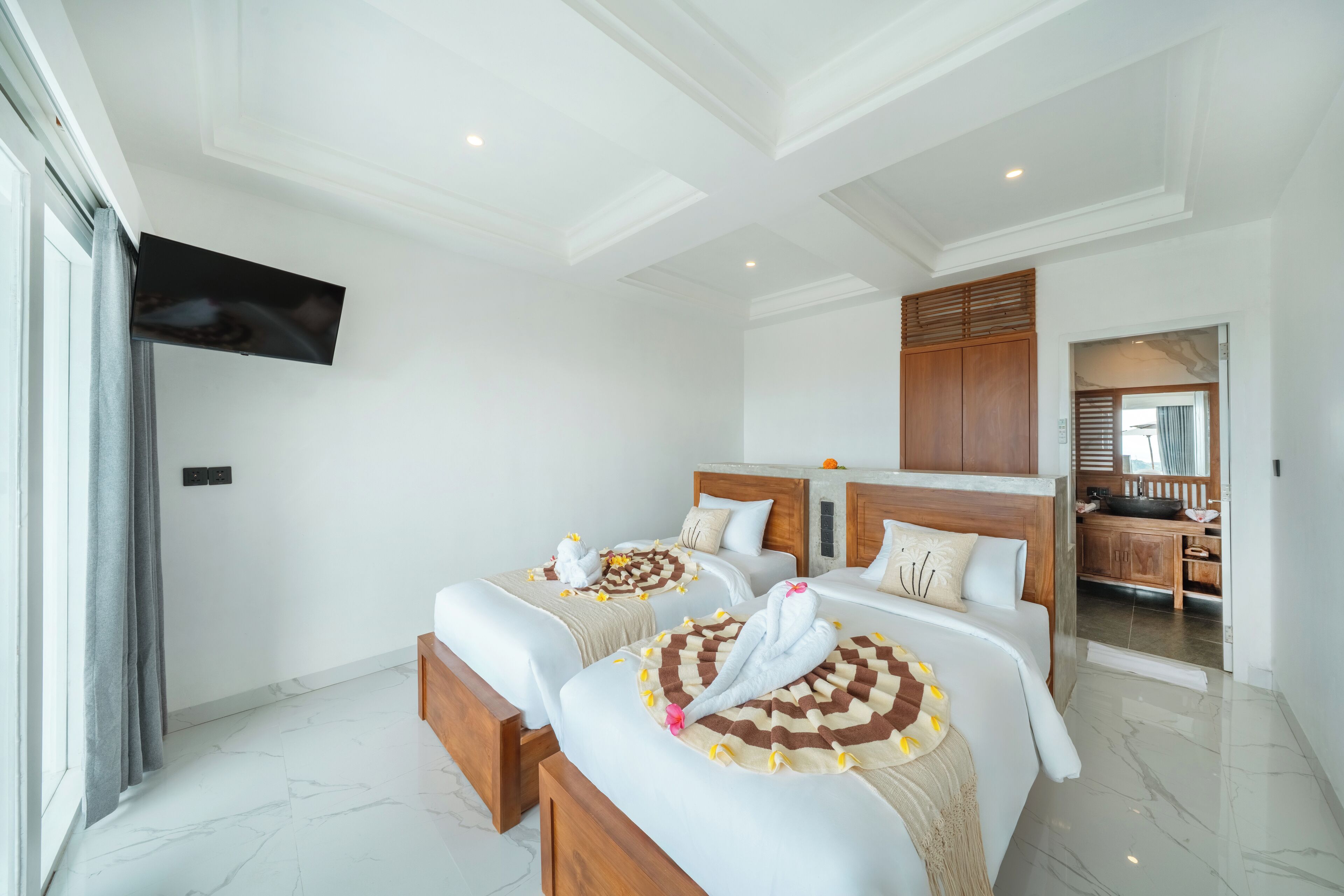 A hotel room with two beds, a TV, and a bathroom visible through an open door.
