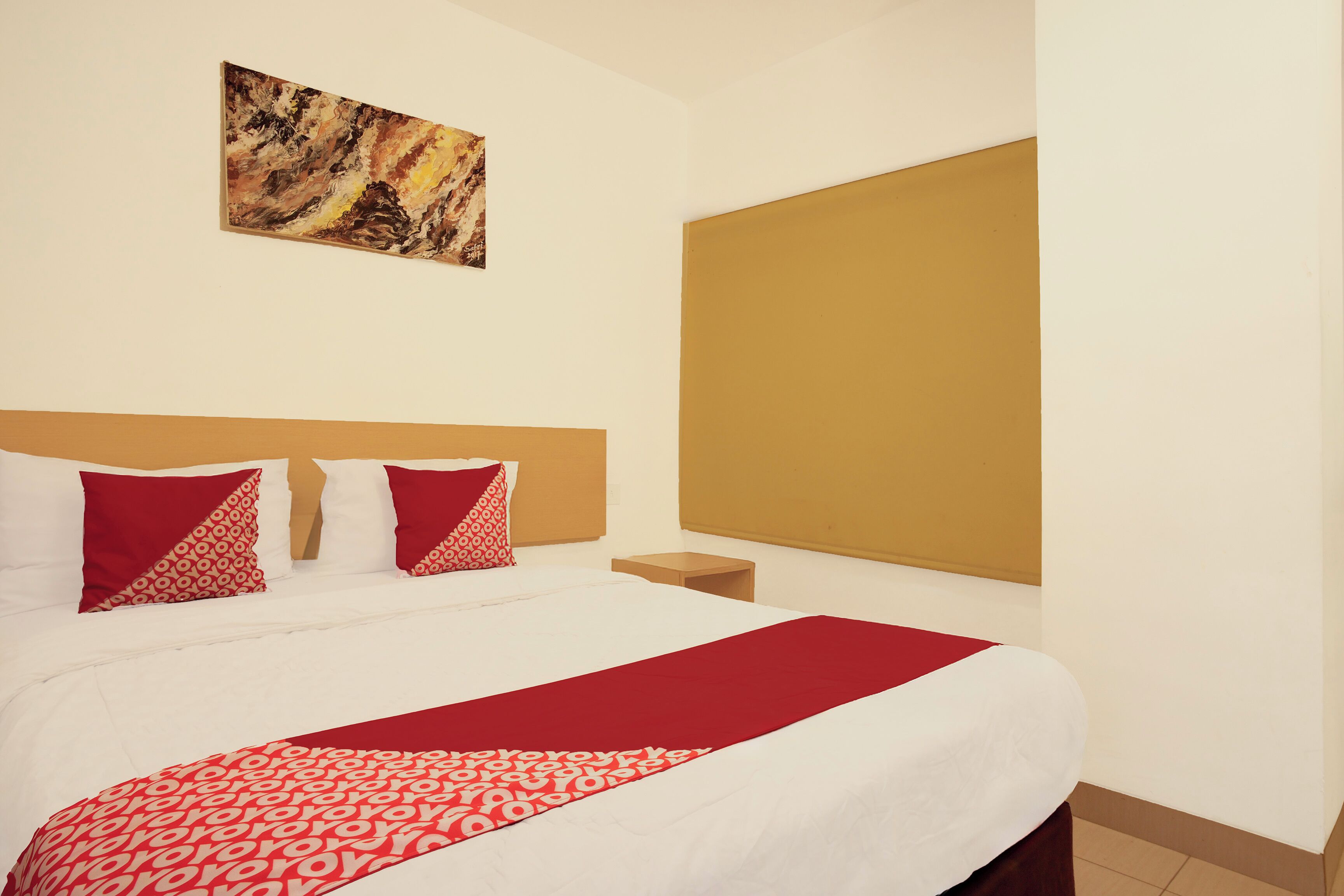 Habitación de hotel con una cama grande, cabecera, mesita de noche, un cuadro en la pared y ventana con vistas.