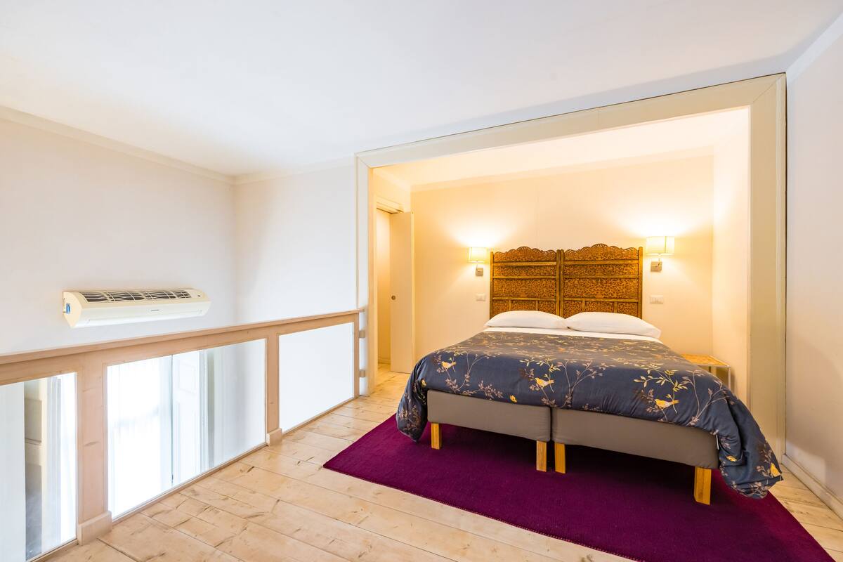 A bedroom with a bed, a purple rug, and a wooden headboard.
