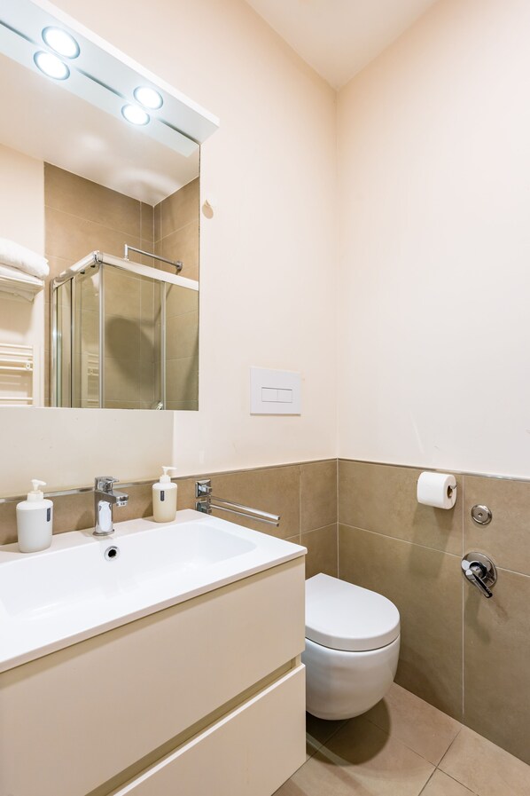Une salle de bain moderne avec un lavabo, un miroir et des toilettes, le tout de couleur blanche.