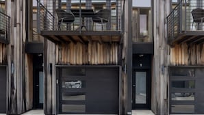Un edificio moderno con fachada de madera, varios balcones y techo plano.