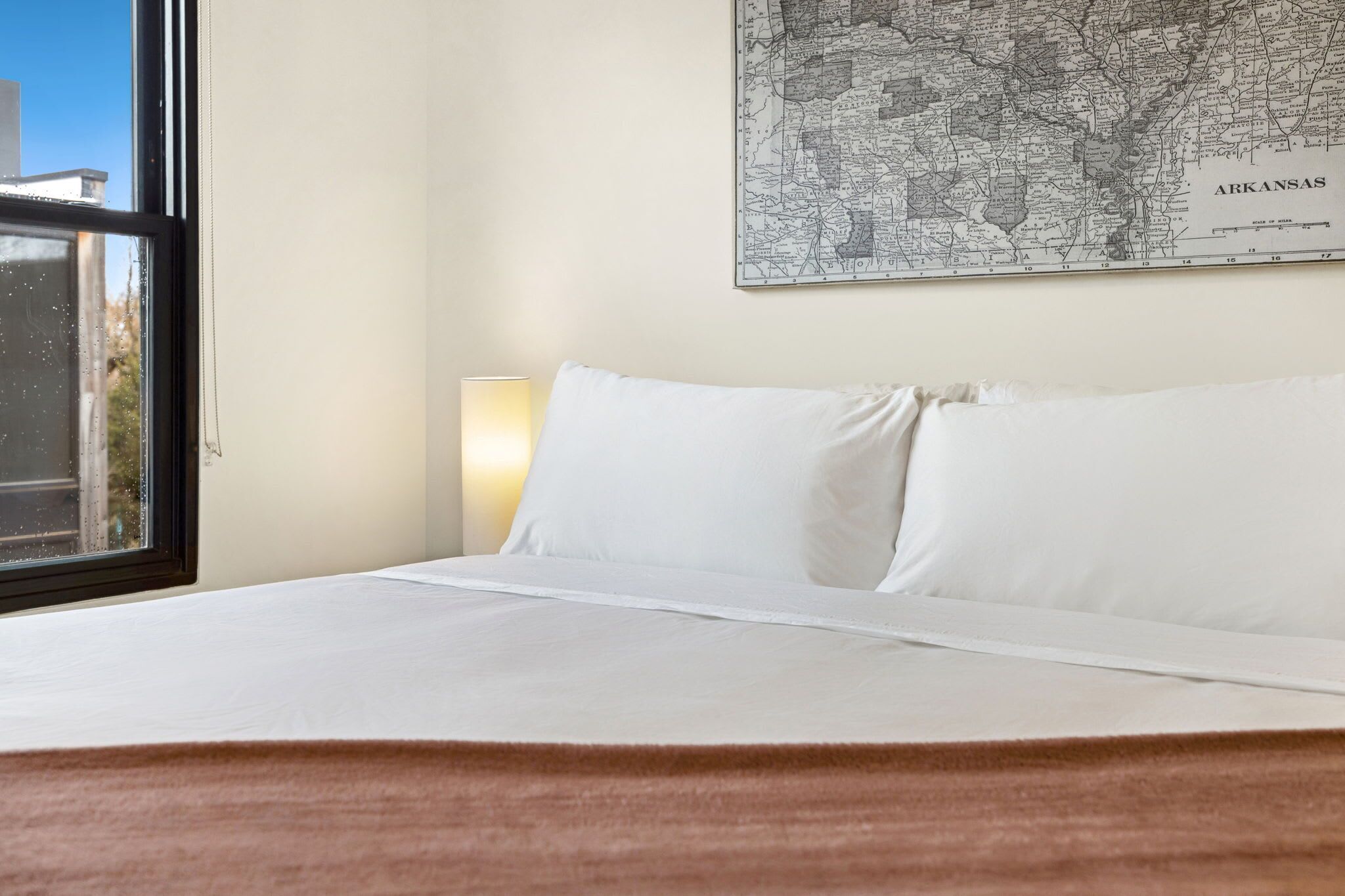 Una habitación de hotel con una cama, un mapa en la pared y una ventana.