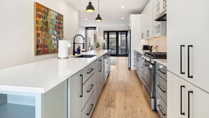A modern kitchen with white cabinetry, a central island, pendant lighting, and a view to the dining area.